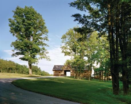 Visitors drive through the bays of a modern barn before arriving at the gravel court and house. The barn's long face appears farmlike, while the short ends express the architectural layers of wall, fabricated truss, and stone water table. A cupola lets light into a workshop's double-height interior.