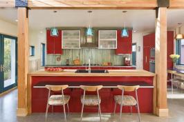 A+straight-on+view+of+The+Red+Cottage%27s+kitchen+shows+off+shiny+red+cabinets+and+glulam+beam+framing%2c+and+a+playful+use+of+color+and+materials..