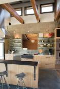 Appliances frame recycled steel shelves on the kitchen wall. Those touches of raw steel and exposed conduit fit Kelly's vision of a vacation home that has "aspects of a Portland loft mixed with a mountain lodge influence."