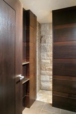 Stone clads this guest bath shower in three forms - large rough-hewn blocks segue into polished mosaics on the wall and smooth tiles on the floor. Dark cabinetry frames the pale variations in stone.