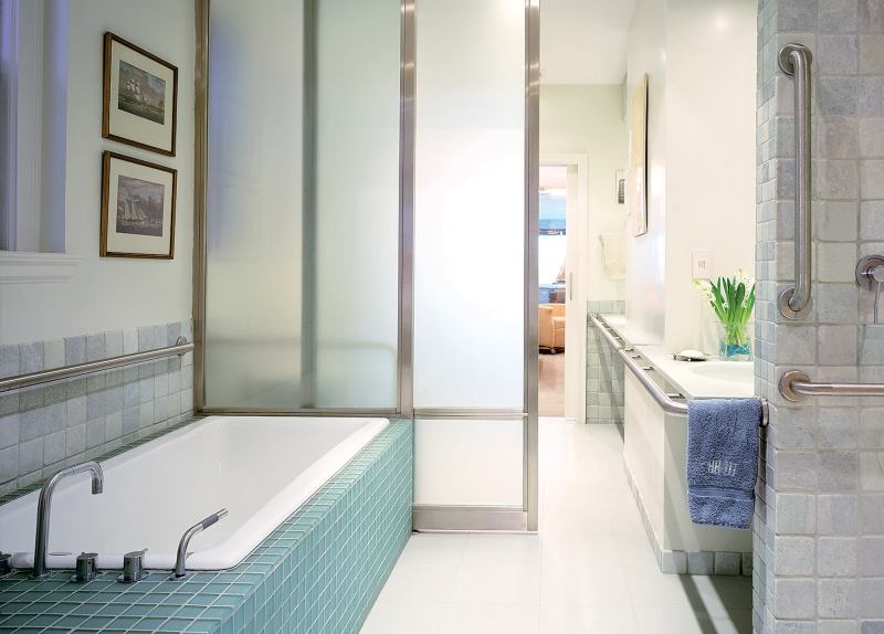 The stainless steel grab rails sparkle in the bright master bath and are emphasized by stainless trim on the glass doors.