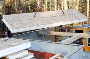 A Panel Pros crew "flies in" a 24-foot R-40 panel for an insulated floor system over an unheated garage in New Hampshire. Able to span 12 feet with a 10-inch panel, SIPs are a no-brainer for insulated floors. But so far the prescriptive SIP code does not mention that use.