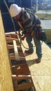 On a Summit Custom Homes jobsite, a framing carpenter wears a safety harness secured to a point above him while working on the roof. He is wearing a hardhat and shoes that have good traction for the slope of the
roof. &nbsp;