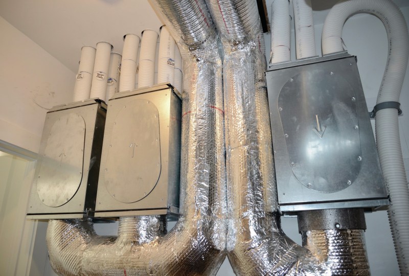 A close-up of the ERV shows the distribution boxes with up arrows indicating fresh air going to primary living spaces and down arrows for the return air.