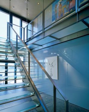 A balcony and three bedrooms on the upper level overlook the water and are reached via the house's glass stairs.