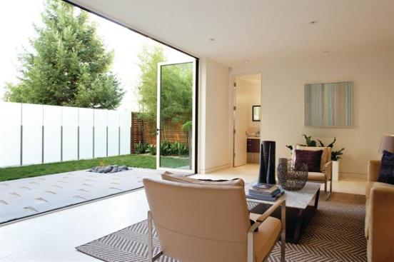 n etched glass privacy fence expands the lower-level family room to take in the compact backyard. A gas-fueled firepit provides an off-center focal point.