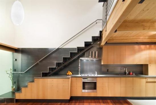 Positioned snugly beneath a steel staircase, this clever kitchen uses beech cabinets to contrast with the space's heavier elements, including its hot-rolled steel backsplash and concrete countertops. The project won a 2009 Residential Architect Design Award. Project: Live, Dine, Sleep, Reno, Nev.; Architect: Hawkins & Associates, Reno