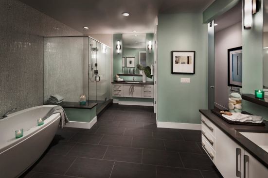 A freestanding tub, floating vanities, linear floor tile, solid countertops, mosaic wall tiles, and cool paint colors create a spalike feel for this bath, selling the room as a haven and a getaway. Builder: Infiniti Home Collection; Merchandiser: HRI Design, Denver