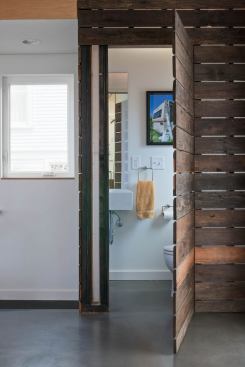 The same re-puprosed car decking used on the exterior also encloses the powder room.