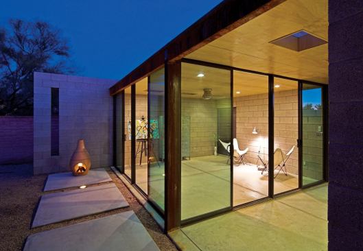 Sliding glass doors open from the studio onto the garden and breezeway, and concrete and rusted steel provide a modern, industrial look.