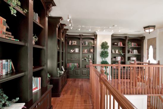 LOFT SOLACE: The L-Shaped loft, accessed only by a spiral stair from the home office below, not only provides a quiet, private place to display and enjoy an extensive book collection, but it also affords a 270-degree view of the lakes (a man-made lake in the front and a natural lake in the back) and the neighborhood.