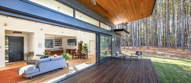 Natural light splashes on the hickory flooring from clerestory windows. The kitchen is visible to the right of the front door.