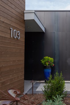 Natural cedar juxtaposed with fabricated steel at the entrance.