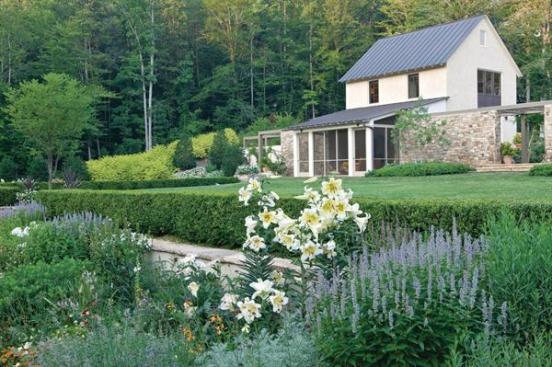 The rear gardens hawthorn allee aligns with the front door and leads to the sunken perennial border, which is shown here in bloom.