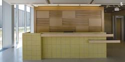 An open reception desk of glazed concrete masonry units, with an abstract backdrop of MDF panels, welcomes relatives and friends of inmates.
