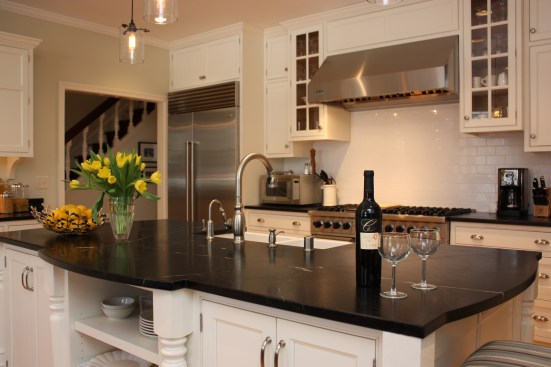 This farmhouse had received several updates and renova-
tions over the years. However, the floor plan was conflict-
ing amongst the kitchen, laundry, mudroom, and powder 
room. A complete reorganization of the first floor was 
achieved through multiple structural changes that al-
lowed for a larger kitchen and created better flow be-
tween adjacent rooms. The kitchen includes custom 
painted cabinetry, a farmhouse style sink, and soapstone 
countertops. A commercial size Viking range, hood, and 
Sub Zero refrigerator bring a theme of stainless steel to 
the kitchen which is accentuated by brushed nickel hard-
ware and island faucet. Specialty lighting, glass door 
cabinets, and a grand, eight foot island are just a few of 
the features that make this kitchen stunning.