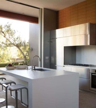 Residential Architect November-December 2009  K + B Studio   project: 543 House, Venice, Calif.; architect: Callas Shortridge Architects, Culver City, Calif.; general contractor: Herman Construction Co., Westlake Village, Calif.; resources: bathroom and kitchen fittings: Dornbracht Americas; bathroom fixtures: Duravit USA; countertops: DuPont (Corian); oven: Miele; patio doors: Fleetwood Windows & Doors; refrigerator: Sub-Zero.   Steel cabinets form a unified front with the stainless appliances. Teak cabinets above inject a note of warmth. The island picks up on the wall assembly's nested "L" shapes and Corian counter.