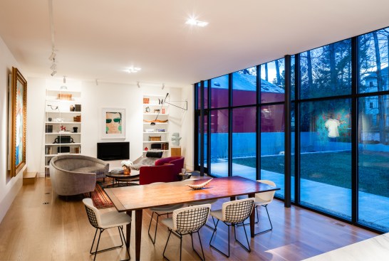 View from the new kitchen to the fireplace that anchors the opposite end of the open space. The glass wall provides views of the backyard and the architecturally diverse neighborhood.