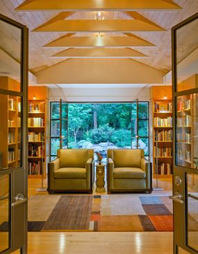 Triple sets of steel framed glass doors link the room to surrounding gardens on three sides.