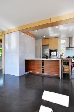 Maple veneer apple plywood  wraps around an open pantry and structural ceiling beam then continues as a slender cabinet that turns into a built-in bench running the length of the dining area.