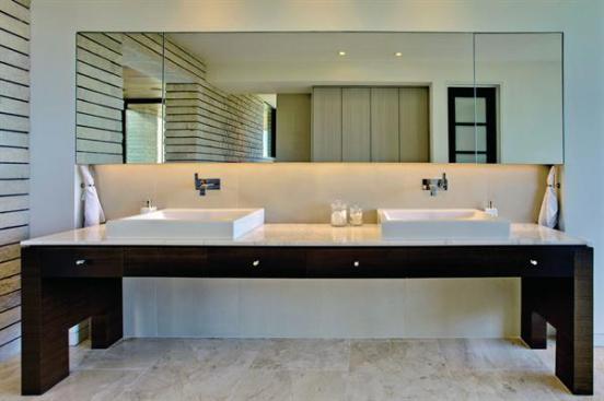 A+double+vanity+is+partially+recessed+into+a+niche+with+mirrored+wall+storage.