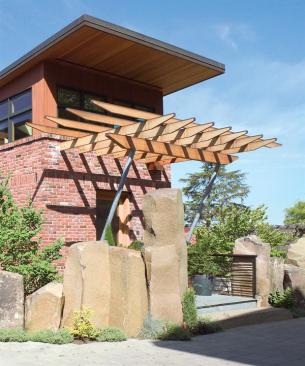 A wall of basalt boulders gives the house a measure of privacy. The entry tower, trellis, and copper-sheathed bay window help define the front facade.