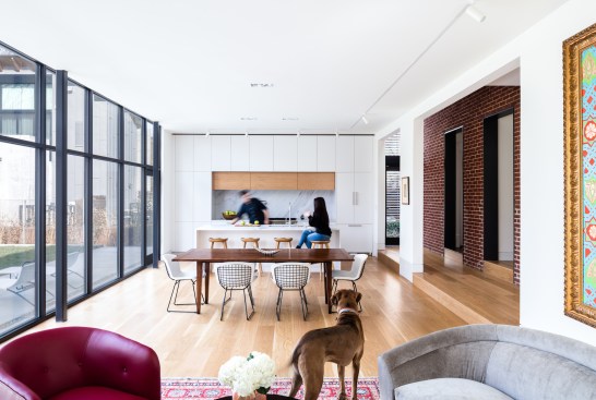 In the transitional space (seen right), the red brick rear wall of the original house stands in contrast to the smooth white walls of the addition and indicates respect for the historic integrity of the old house.