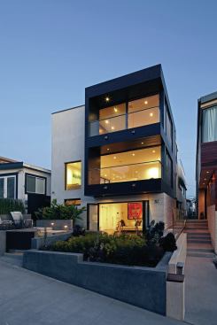 A 1960s duplex converted to a single-family home, the building is located in a densely developed beach community.