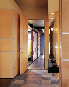 Charcoal gray siding and red accent walls jazz up the home's exterior. A continuous bench running right through the entry wall, below, helps knit inside and outside together.