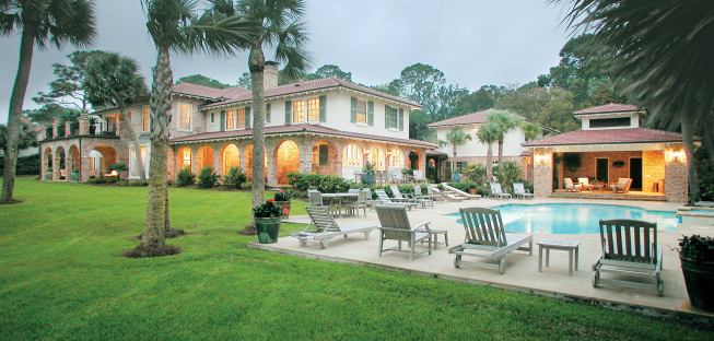 A major remodel to this 75- year-old beach "cottage" transformed the servant's kitchen to a sunny space. It opens to what was an old service yard, but now is a series of beautiful and functional outdoor rooms—covered loggias, a new pool house, new pool, and spa. Because the beachfront site can flood, design/builder Michael Thomas raised the pool house two steps and then raised the pool house bathroom another two steps.