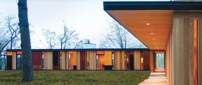 In an effect inspired by the forest that surrounds it, views through this new lakeside home shift with one’s perspective. Its unfinished red cedar siding will gray to blend with the tree trunks.
