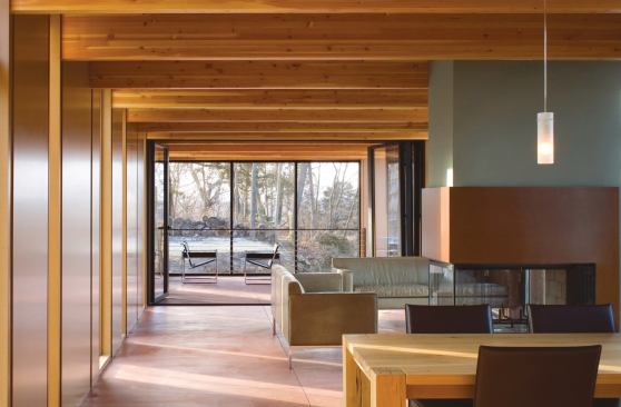 The linear, open-plan interior wears a simple palette of pigmented concrete floors, clear-finish MDF wall and ceiling panels, and laminated fir structural beams.