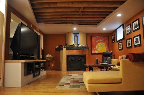 The design program for this small basement (originally used as a dog kennel) included a bar, a full bathroom, an entertainment and living area with a fireplace, an artistic waterwall feature, and enhanced storage space. The clients wanted artistic elements that could fit into a small budget.