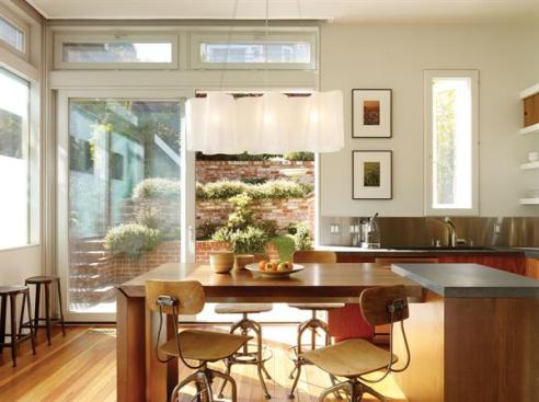 A distinctive 4-inch gap separates the stone-topped countertop from the adjacent drop-leaf table. Concealed metal supports beneath the tables walnut-veneer top allow the piece to open up to accommodate 10 people.
