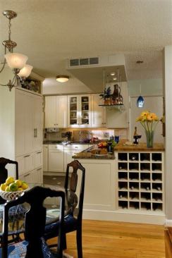 For this mid-range kitchen&nbsp;in a small two-bedroom apartment, Jennifer Gilmer Kitchen & Bath removed the wall separating the living room, dining room, and kitchen. To make up for lost space, the firm suspended a glass shelf above the peninsula.