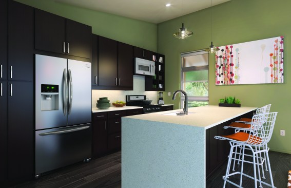 The open kitchen is outfitted with an Energy Star-labeled Frigidaire Gallery refrigerator and a Gallery dishwasher that automatically adjusts the cycle time based on how much cleaning is needed. Also included are a Kohler enameled cast-iron sink made of 80 percent recycled materials, a Kohler low-flow touchless faucet, Advanta cabinets, and Cosentino countertops made of 75 percent recycled materials.
