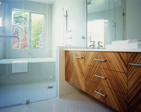The top-fl oor master bedroomopens onto a rooftop deck.Two fl oors below, a shelteredoutdoor space tunnels throughthe building, joining its privateand public sides (bottom left).Bath cabinets are faced inzebrawood veneer (bottom right).