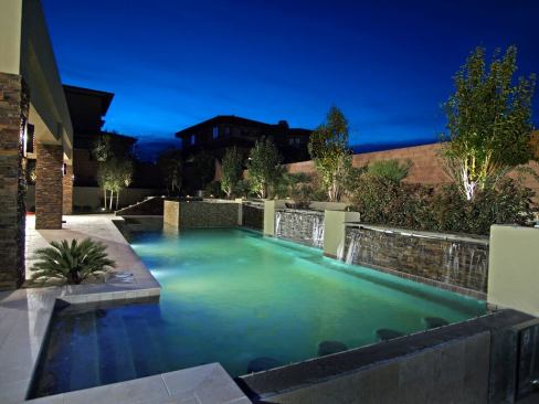 The kitchen and sitting area open onto a patio and outdoor living area that features an infinity-edge pool, rock-wall waterfalls, and hot tub.
