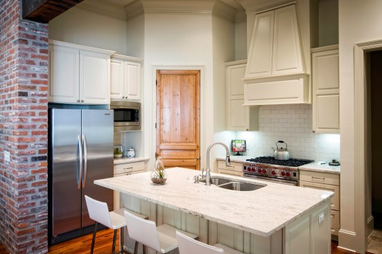 This white kitchen is enhanced by the textured finishes of the wooden door and exposed brick wall.Project: Perkins Lane by LRK Architects&nbsp;