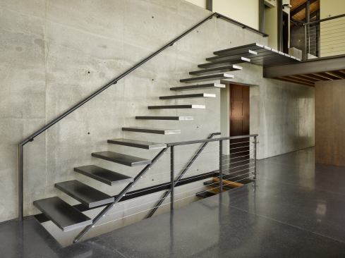 This masterful staircase, designed by 
Lawrence Architecture, was formed by casting rods directly into the home’s main concrete wall, then fitting them with steel tubes for the treads.