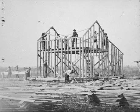 Figure 1: Ten men building a wood frame house on a Omaha Reservation in Nebraska in 1877  (Photo by William Henry Jackson: The National Archives, Smithsonian Institution) Source: National Endowment for the Humanities, http://www.neh.gov/files/divisions/public/images/05_balloon-framing_resized.jpg