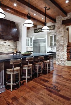 High-low finishes such as a distressed copper range hood, a gleaming stainless fridge, rough-hewn ceiling timbers, and dark wood floors help compose a look that's both industrial and warm. 