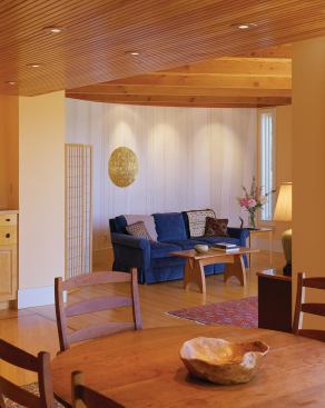 A section of fir-paneled ceiling defines the dining area and creates a transition from the kitchen's finished ceiling to the open beams of the living room.