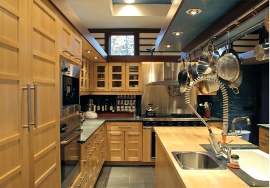 A high-capacity custom pot rack hangs at the same level as the light soffit that rings the kitchen and adjacent nook. De Vido used the lowered scale—both hover 7 feet above the floor—to give the more personal spaces some intimacy.