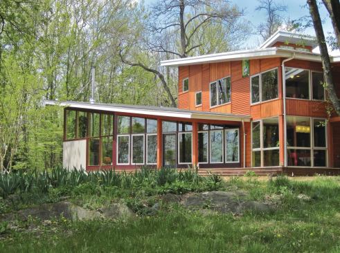 Horizontal and vertical cedar siding adds interest and texture to the exterior of the new home. The siding is decorated with art panels, as seen under the roofline in this photo. The owners sent the panels to friends and relatives to be painted. The contractor inserted the panels into the cedar siding.