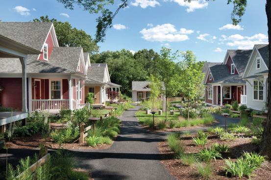 Low-maintenance features such as small yards facing a common green, red cedar shingles, fiber-cement cladding, and cellular PVC trim appeal to the targeted demographic.