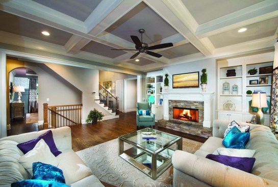 The spacious, two-story family room in the Brentwood model at Ruth’s Farm in Alpharetta, Ga., comes with a fireplace and optional built-in shelving, and peeks into the home’s separate, formal dining room.
